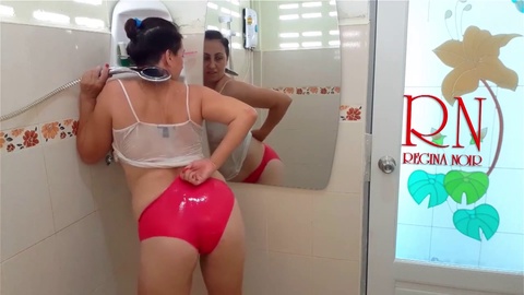La donna si fa la doccia in una maglietta e un paio di pantaloncini.