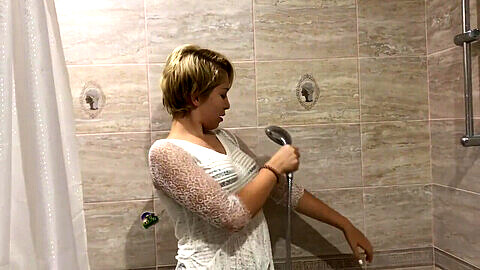 Chica mojada se baña completamente vestida con una camisa semi-transparente