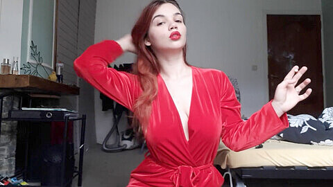 Affascinante ragazza in uno splendido abito rosso si concede un feticismo del fumo